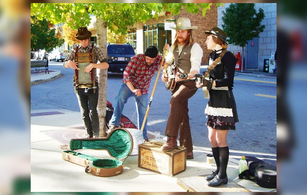 Four street acoustic musicians, known as buskers, playing instruments on a street in Asheville
