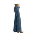 A side profile view of a person wearing blue denim flare jeans with brown cowboy boots, shown against a plain white background.