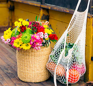 Wicker basket with colorful flowers and a market bag with oranges, in the back of a vintage truck