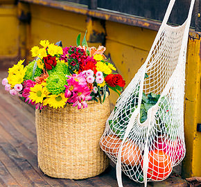 Wicker basket with colorful flowers and a market bag with oranges, in the back of a vintage truck