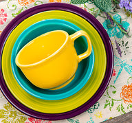 Colorful Fiesta dinnerware arranged on a floral placemat.