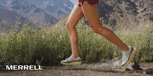A person running on a rugged mountain trail while wearing Merrell Agility Peak 6 technical trail running shoes