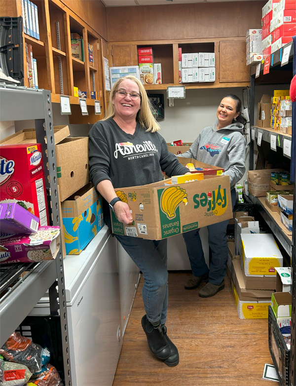 Lisa, president of Mast Store, and Jessa move supplies at the Hunger Coalition