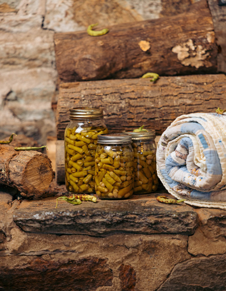 Canned green beans, firewood, and a quilt stacked on a hearth