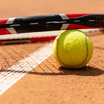 A tennis ball and racquet on a clay court