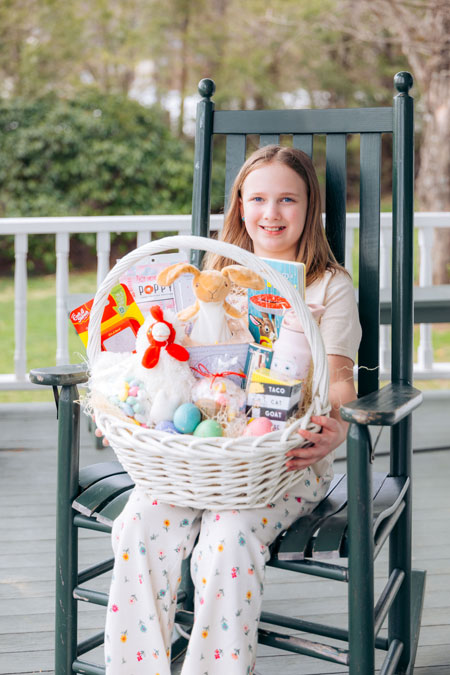 Young girl sitting in a rocking chair with an Easter basket.
